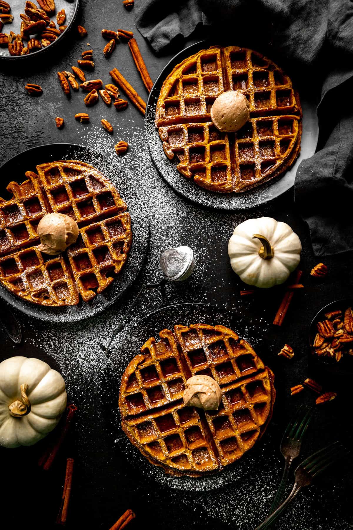 Three pumpkin waffles, two white pumpkins and scattered pecans.