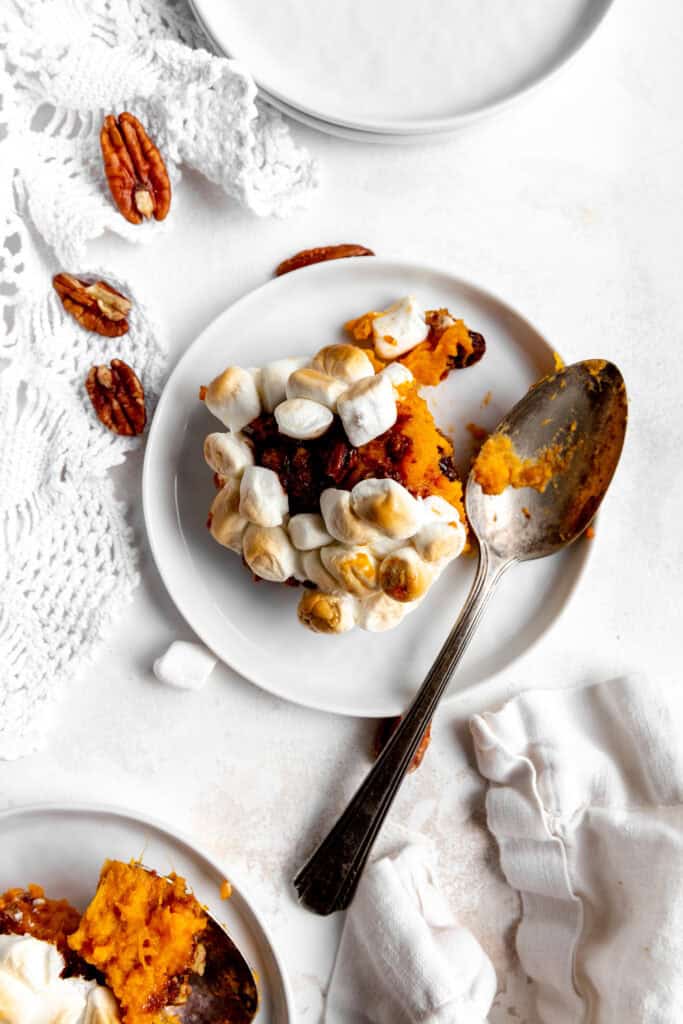 Helping of sweet potato casserole on a white plate with a spoon.