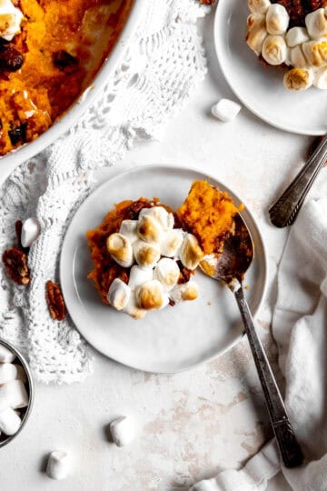 Helping of sweet potato casserole on a white plate with a spoon.