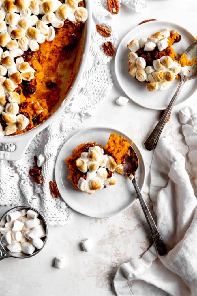 Two plates of sweet potato casserole and a small cup of marshmallows.