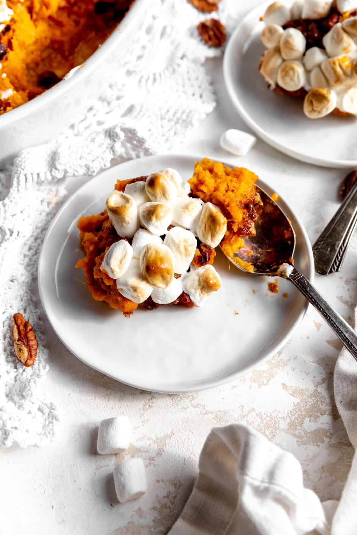 Sweet potato casserole on a white plate surrounded by scattered marshmallows.
