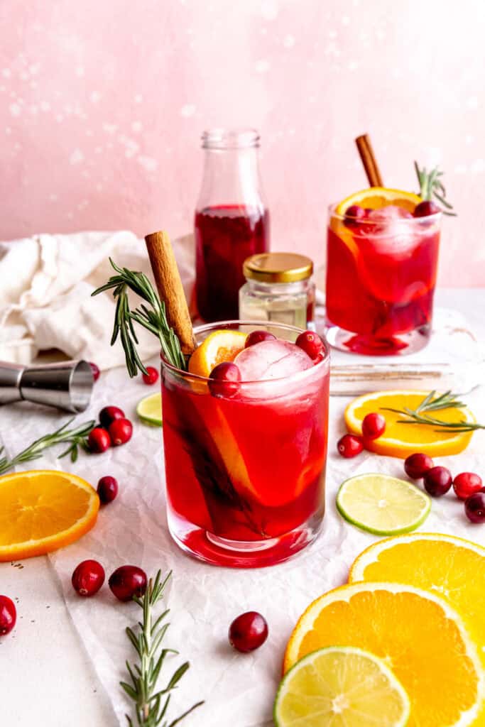 Two cranberry margaritas, fresh orange slices and a jug of linen napkins.