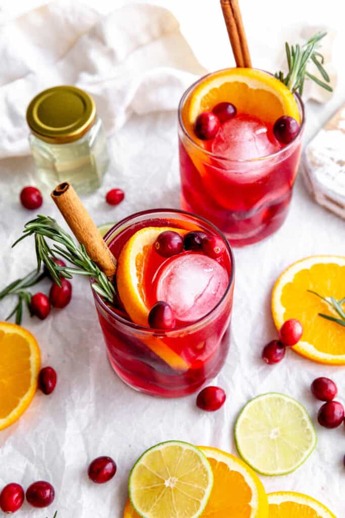 Two cranberry margaritas, orange slices and a linen napkin.