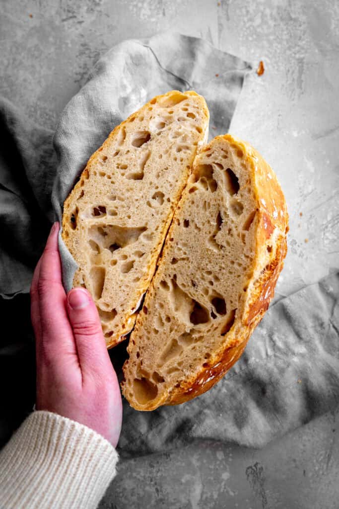 Hand holding a loaf of bread that has been sliced in half.