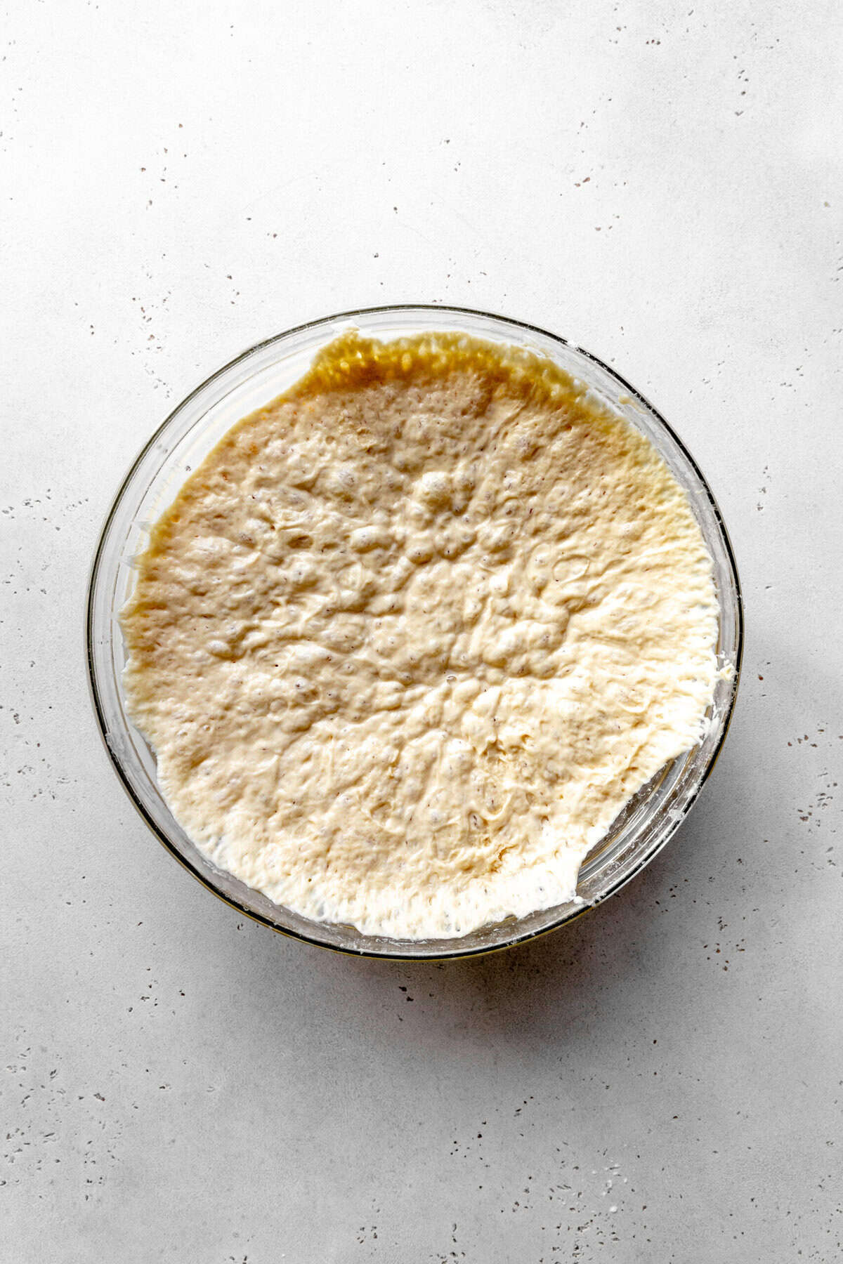Proofed bread dough in a glass bowl.