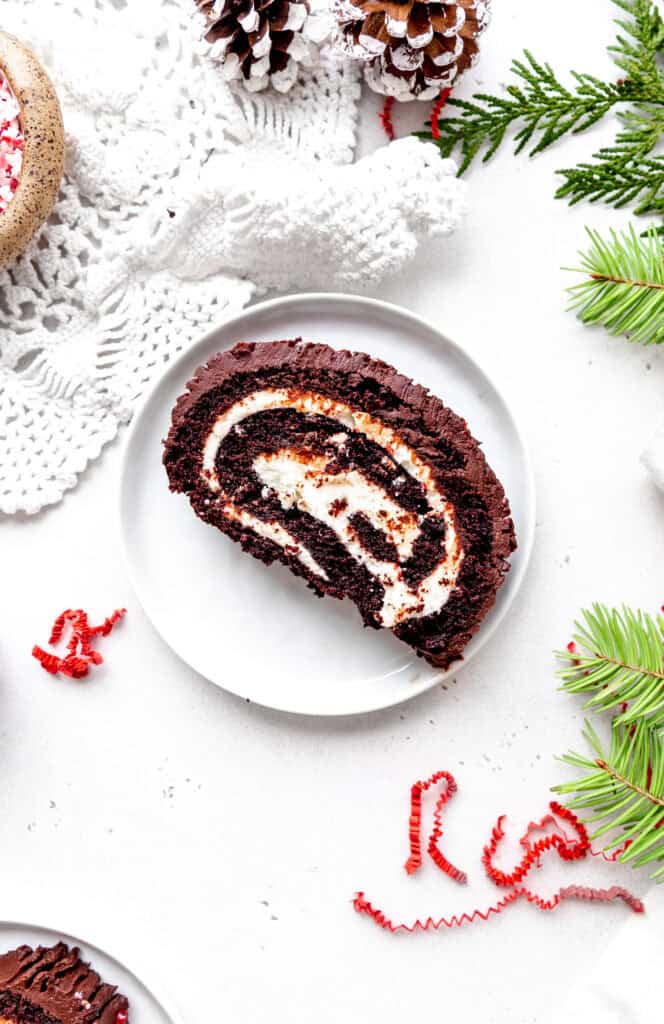 Slice of a peppermint yule log on a white plate.