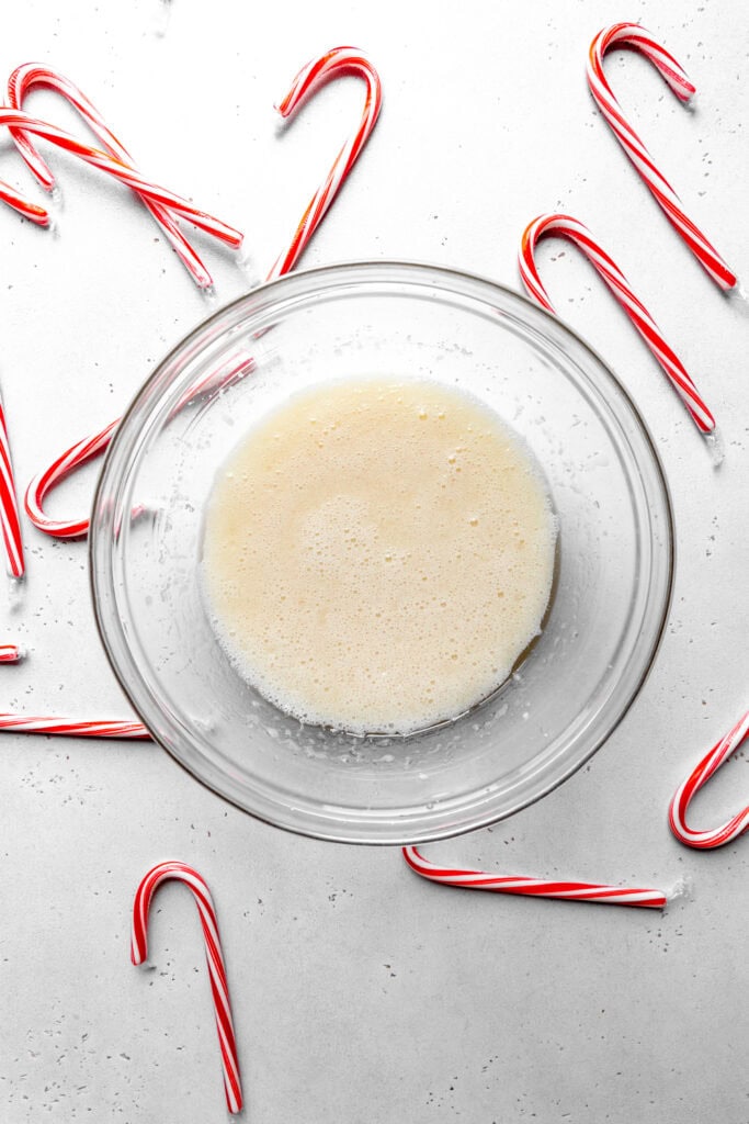 Glass bowl of milk and sugar surrounded by candy canes.