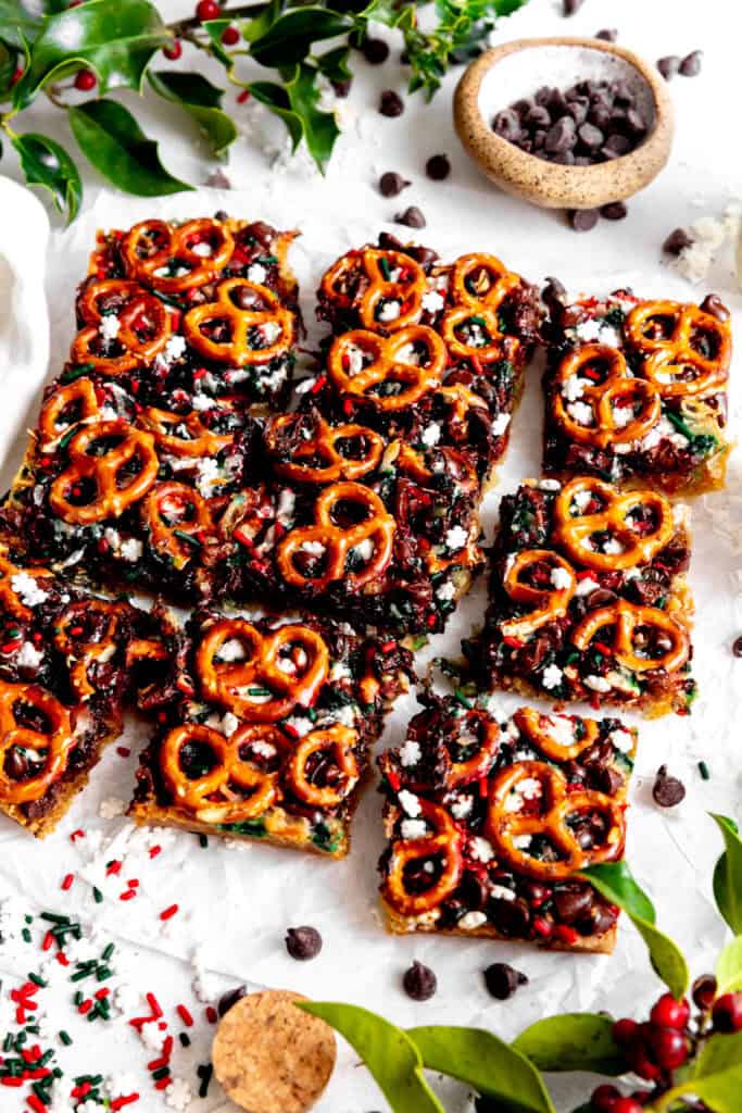Christmas 7 layer bars on a white surface and a cup of chocolate chips.