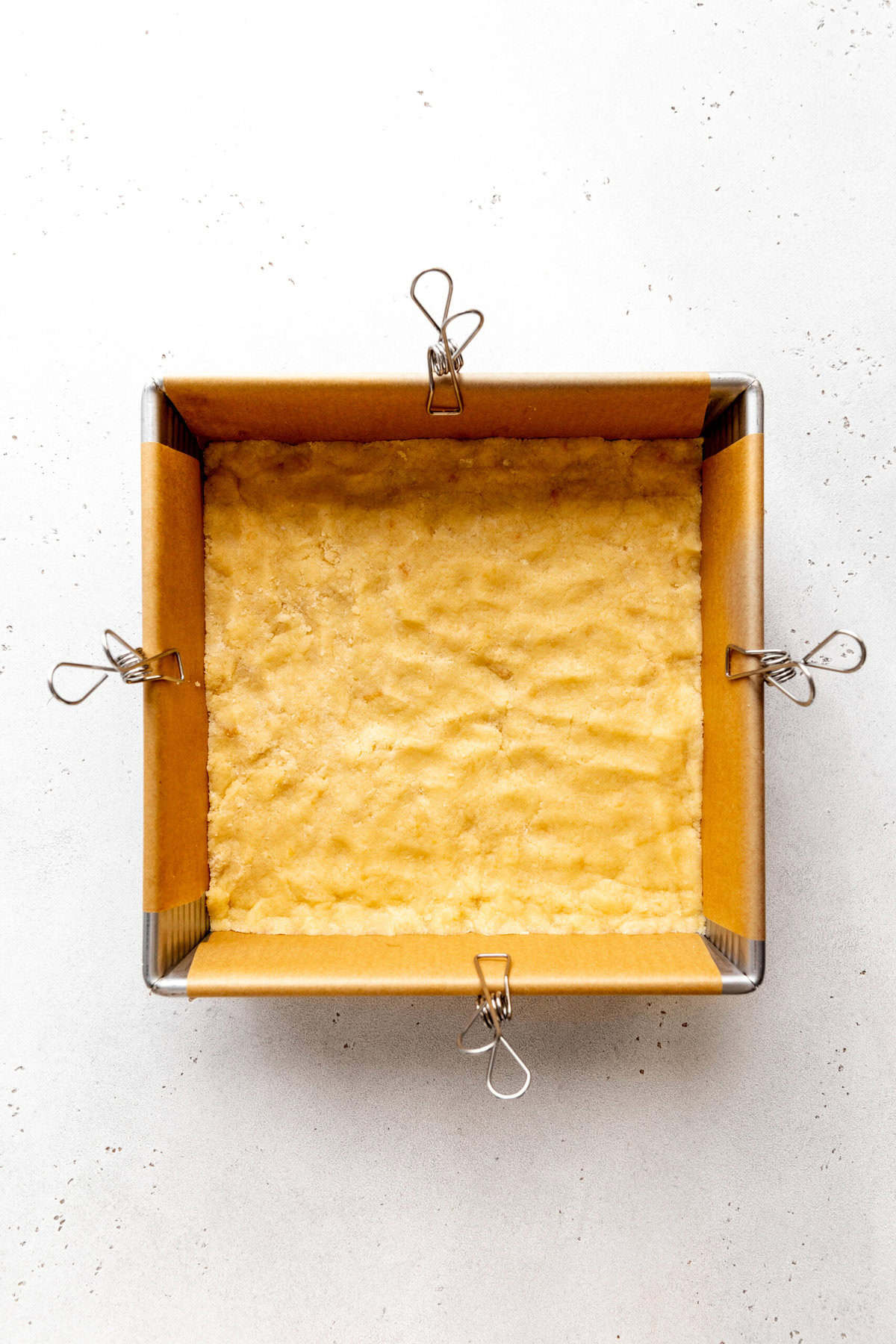 Unbaked sugar cookie dough pressed into a square pan.