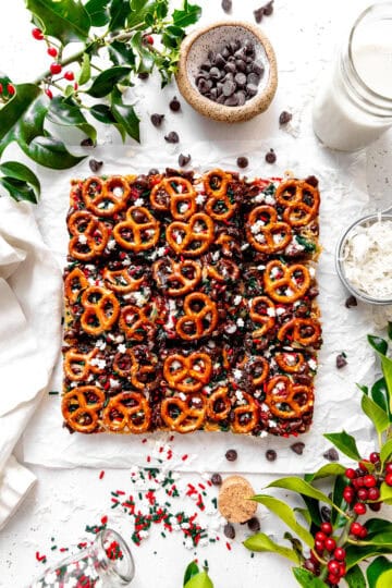 Christmas 7 layer bars, a glass of milk, a cup of chocolate chips and a cup of coconut shreds.