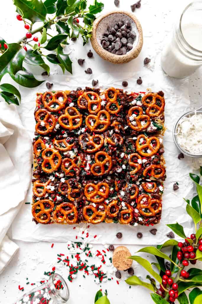 Christmas 7 layer bars, a glass of milk, a cup of chocolate chips and a cup of coconut shreds.