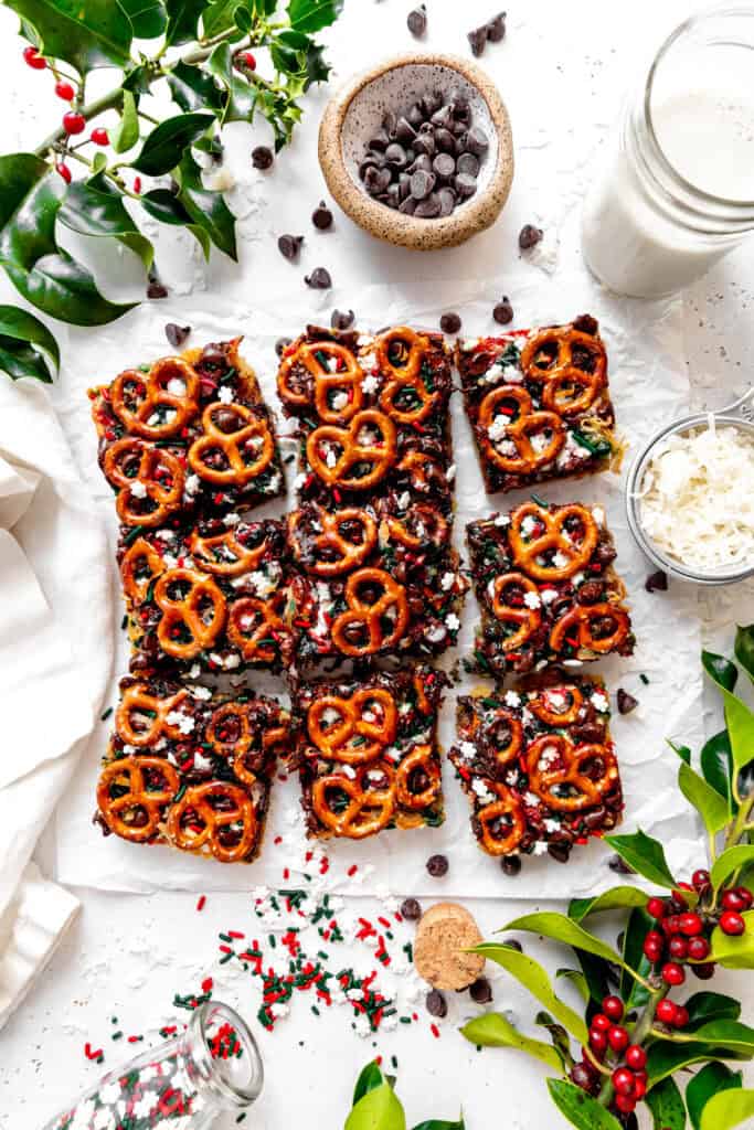 Christmas 7 layer bars, a glass of milk, a cup of chocolate chips and a cup of coconut shreds.