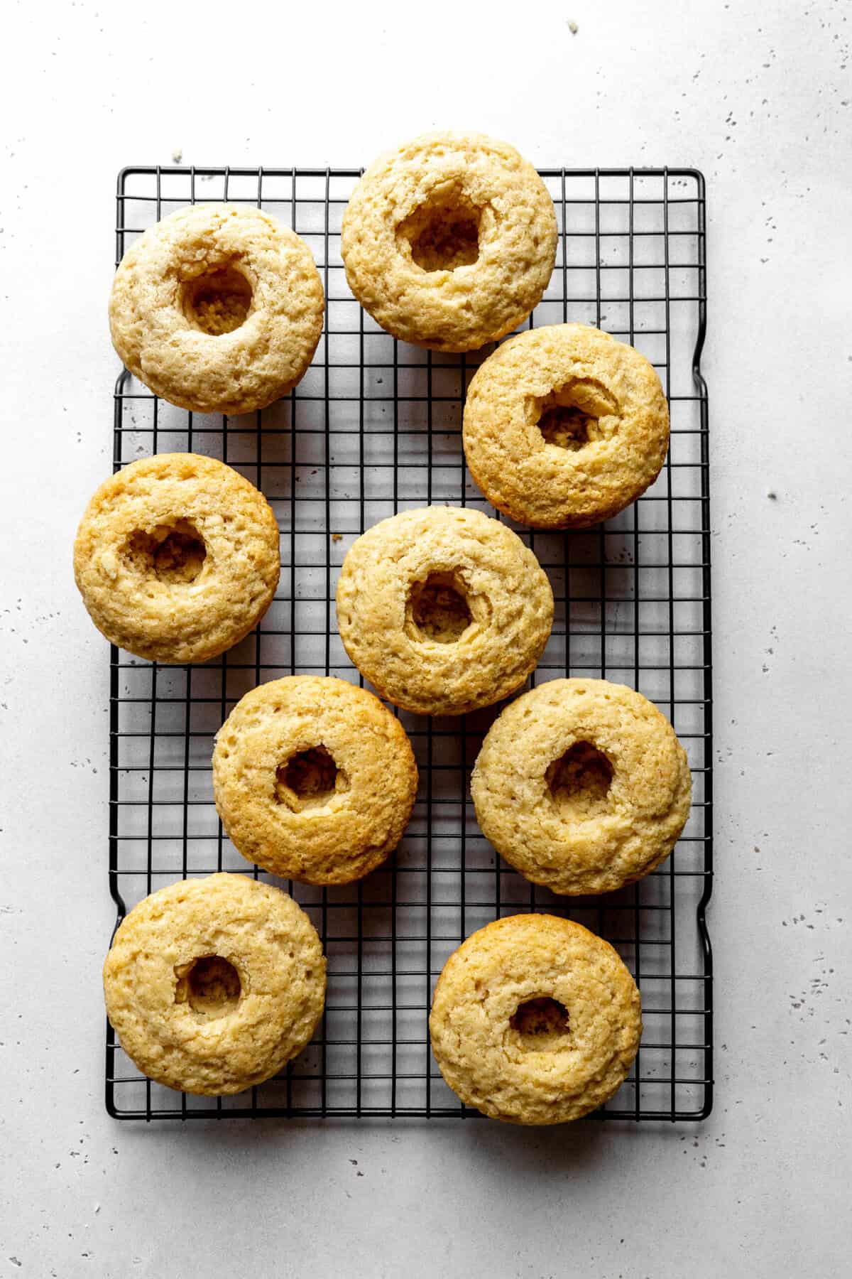 Baked coconut cupcakes on a cooling rack with centers removed.