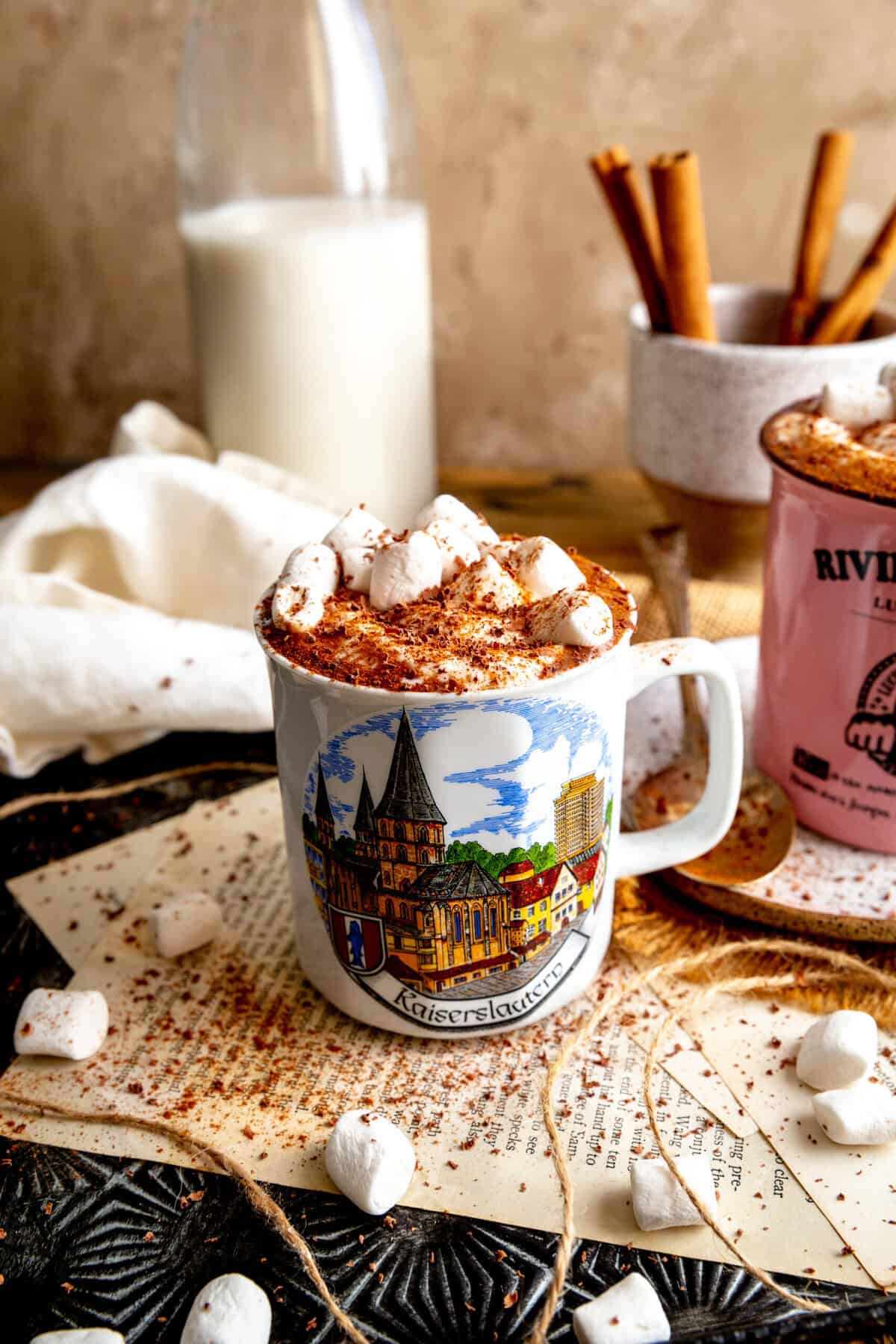 Mug of Mexican hot chocolate topped with whipped cream, marshmallows and cinnamon.