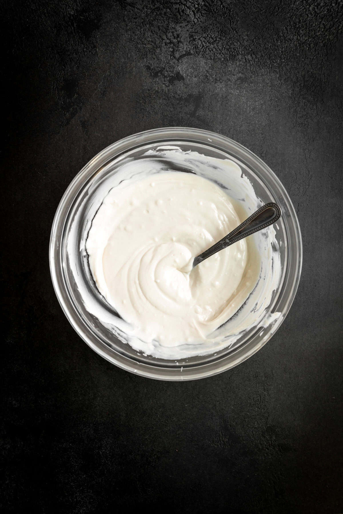 Glass bowl of melted white chocolate with a spoon.