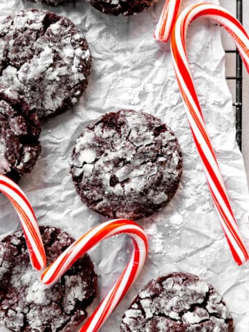 Peppermint crinkle cookies on white parchment with candy canes.
