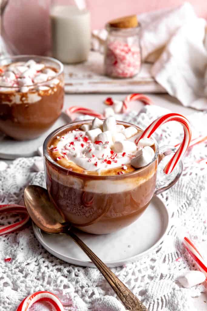 Two mugs of peppermint hot chocolate, candy canes and a white linen napkin.
