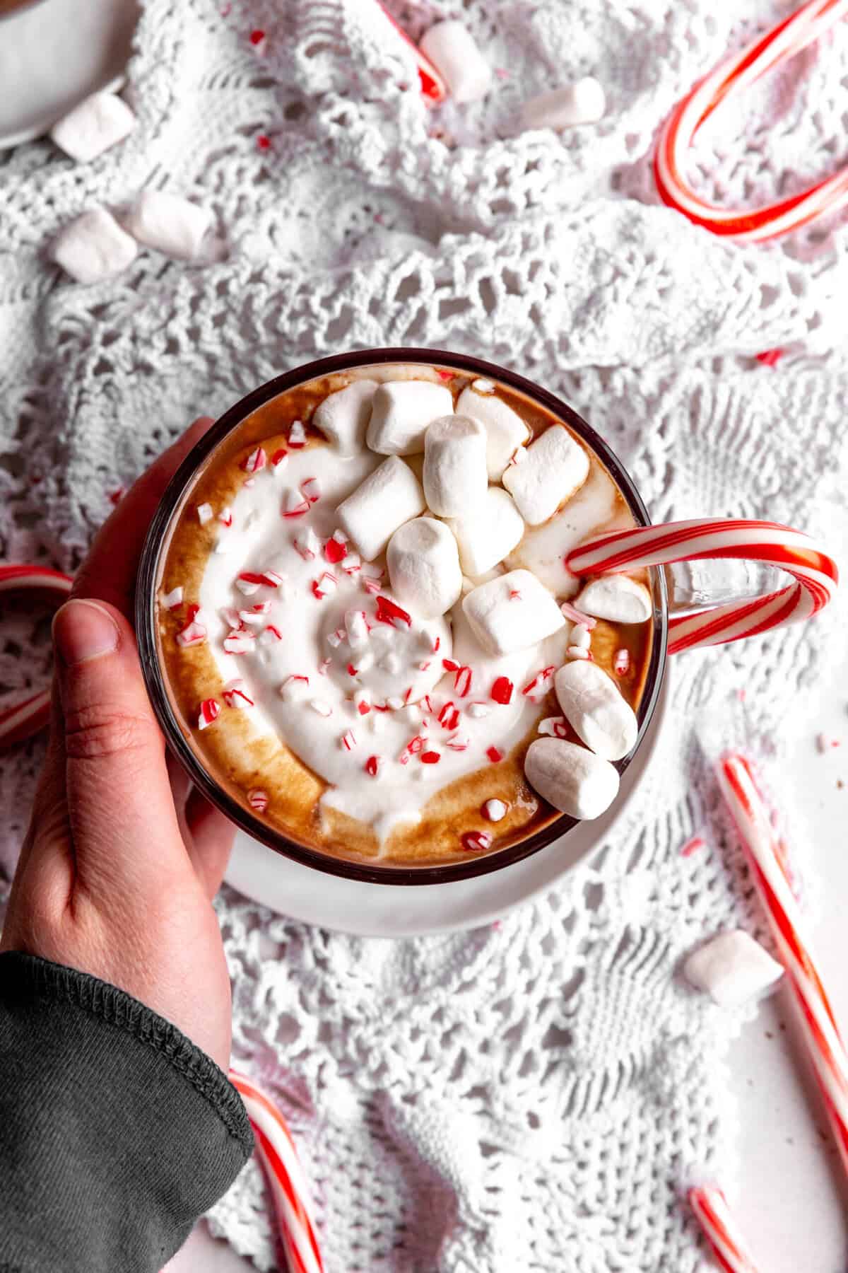Hand cupping a mug of vegan peppermint hot chocolate.