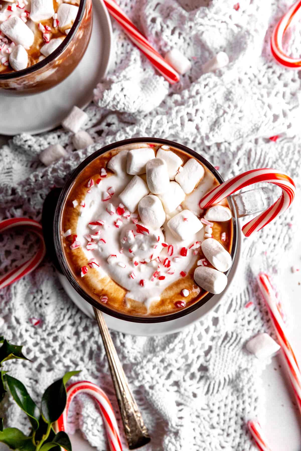 Candy cane in a mug of hot chocolate topped with marshmallows.
