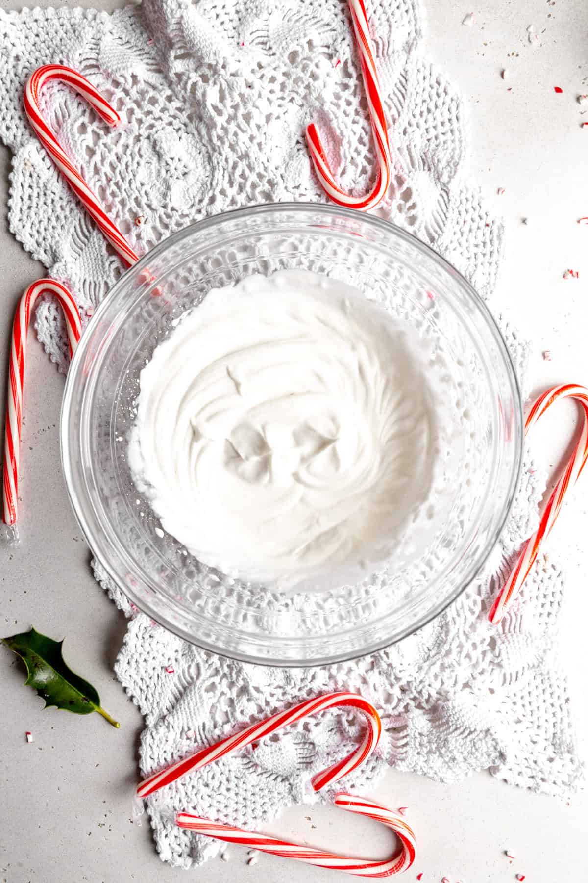 Glass bowl filled with whipped cream surrounded by candy canes.
