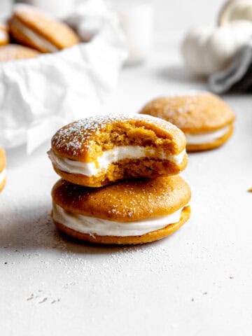Pumpkin whoopie pie with a bite taken out of it on top of another whoopie pie.