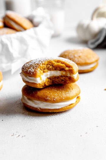 Pumpkin whoopie pie with a bite taken out of it on top of another whoopie pie.