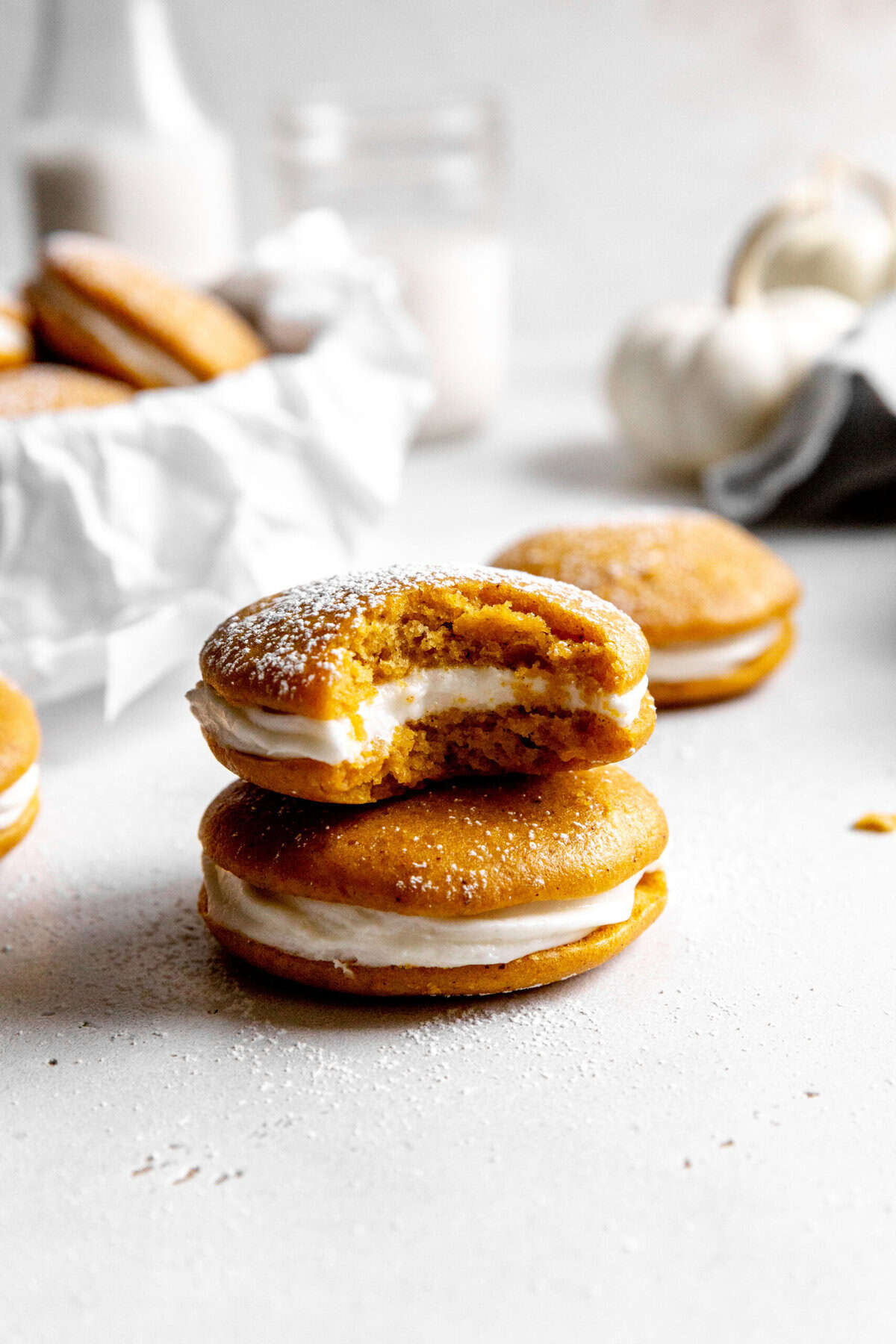 Pumpkin whoopie pie with a bite taken out of it on top of another whoopie pie.