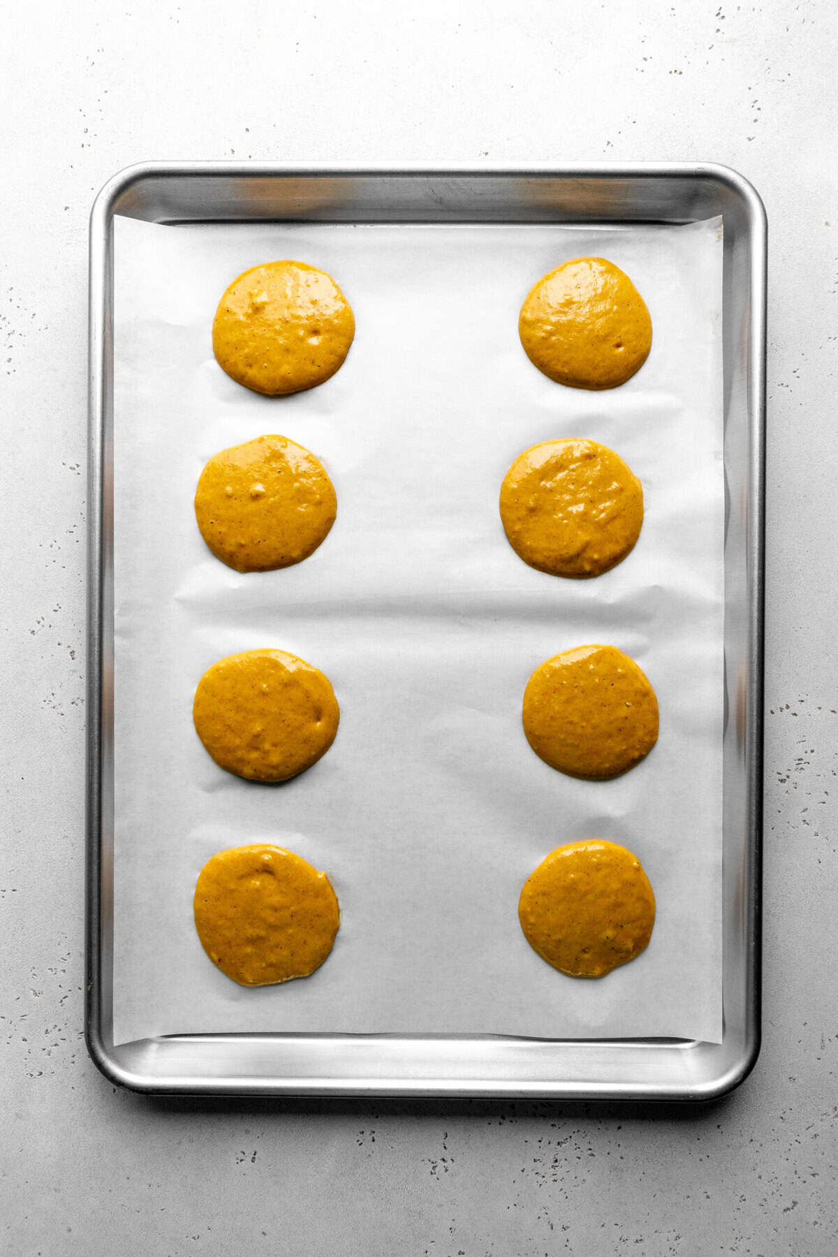 Unbaked pumpkin whoopie pies on a baking sheet.