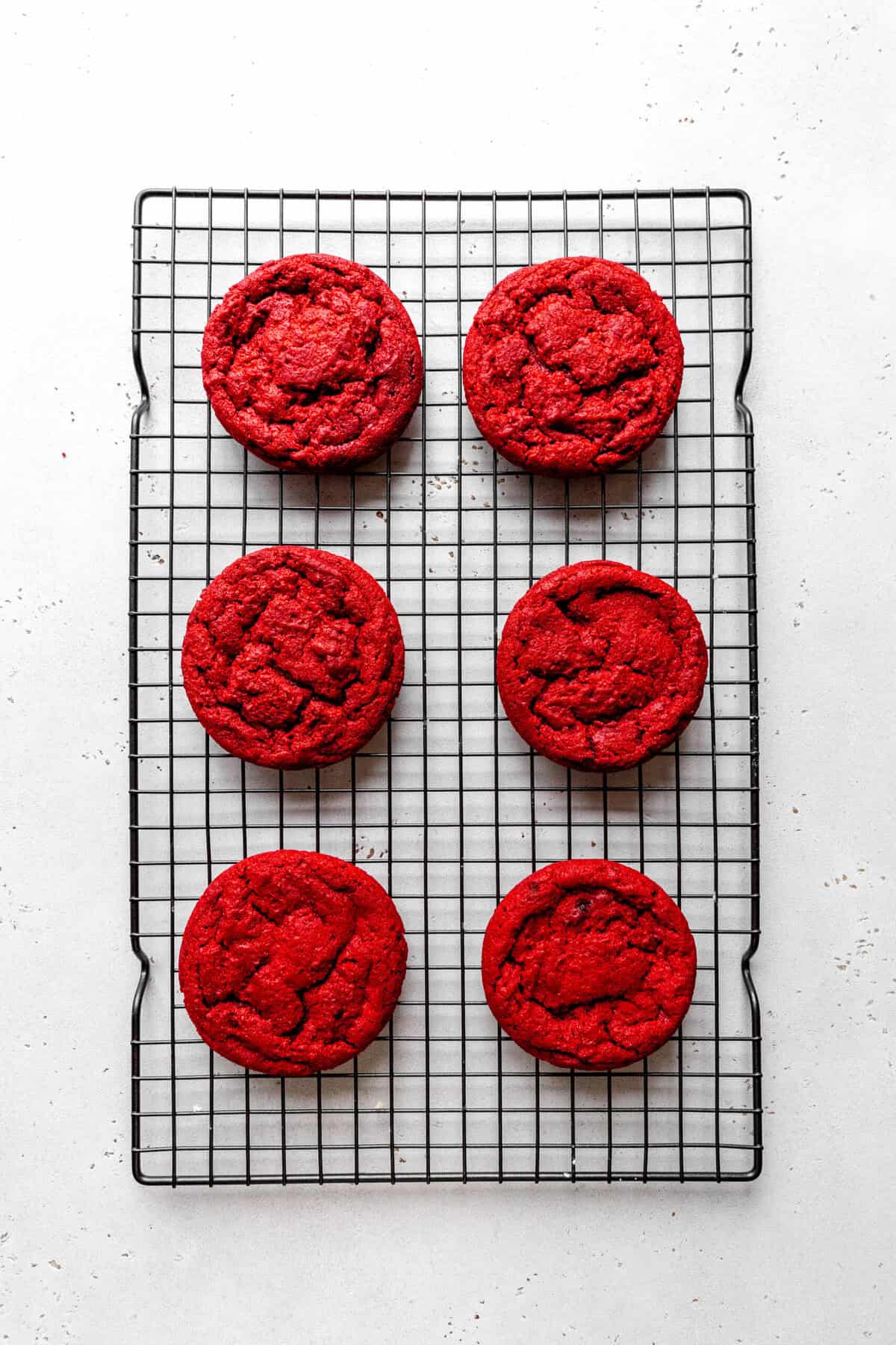 Baked red velvet cookies on a wire cooling rack.