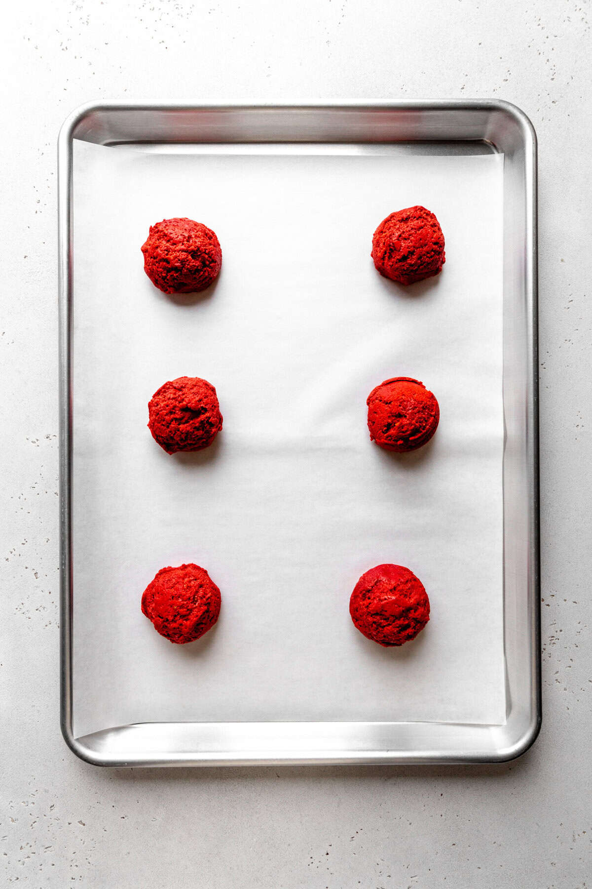 Unbaked red velvet cookies on a baking sheet.