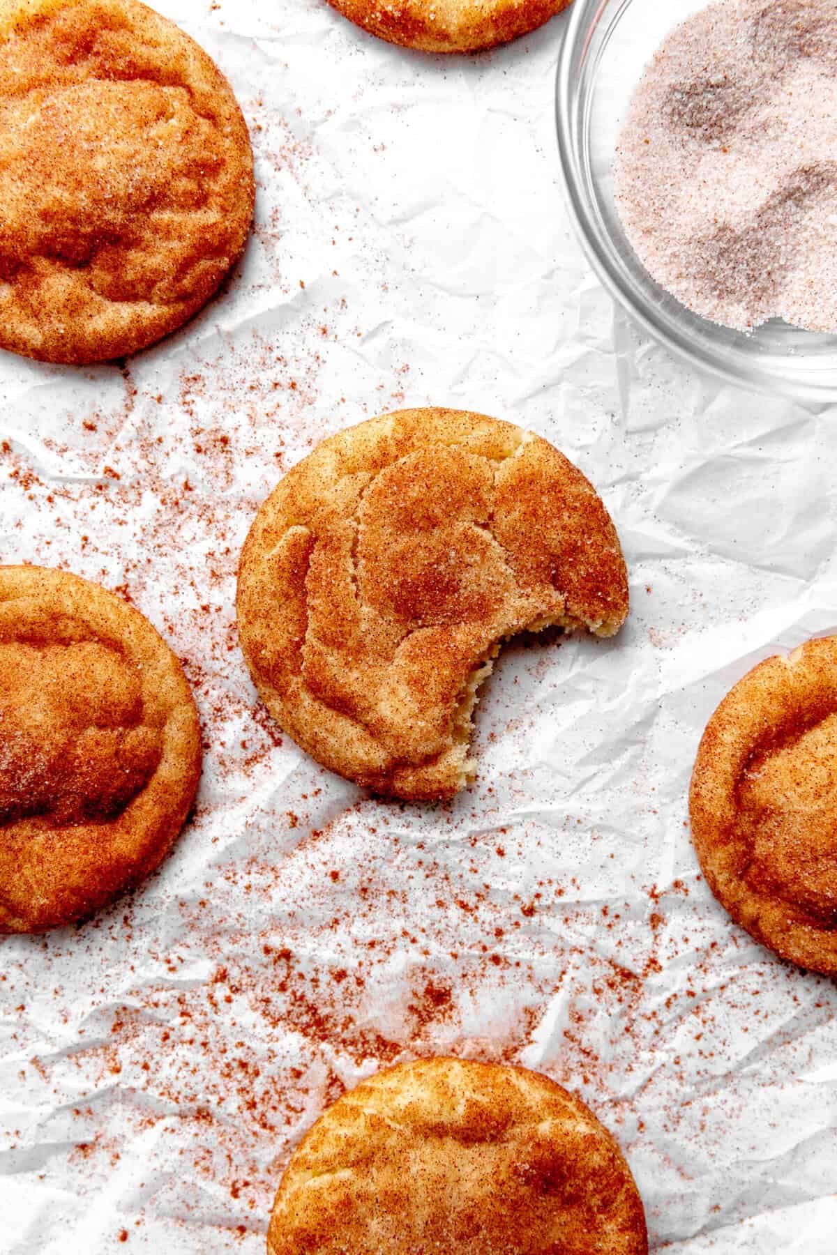 Snickerdoodle cookie with a bite taken out of it surrounded by more cookies.