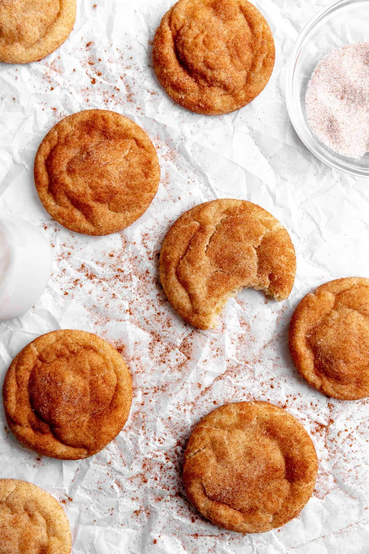 Snickerdoodle cookies on a white surface with a jug of milk.