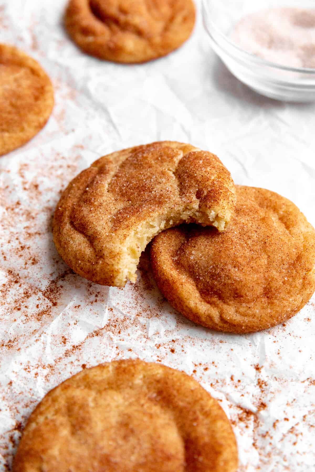 Snickerdoodle cookie with a bite taken out of it propped on another cookie.