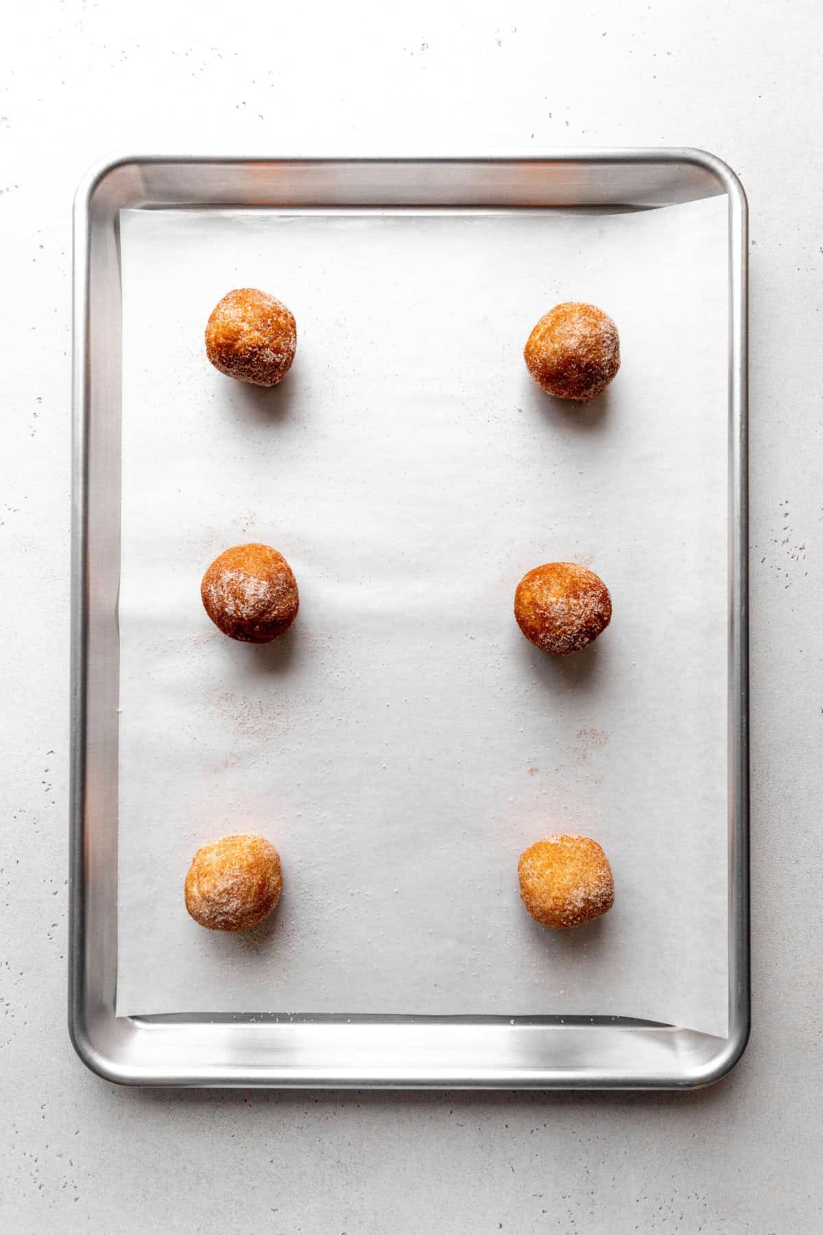 Unbaked snickerdoodle cookies on a baking sheet.
