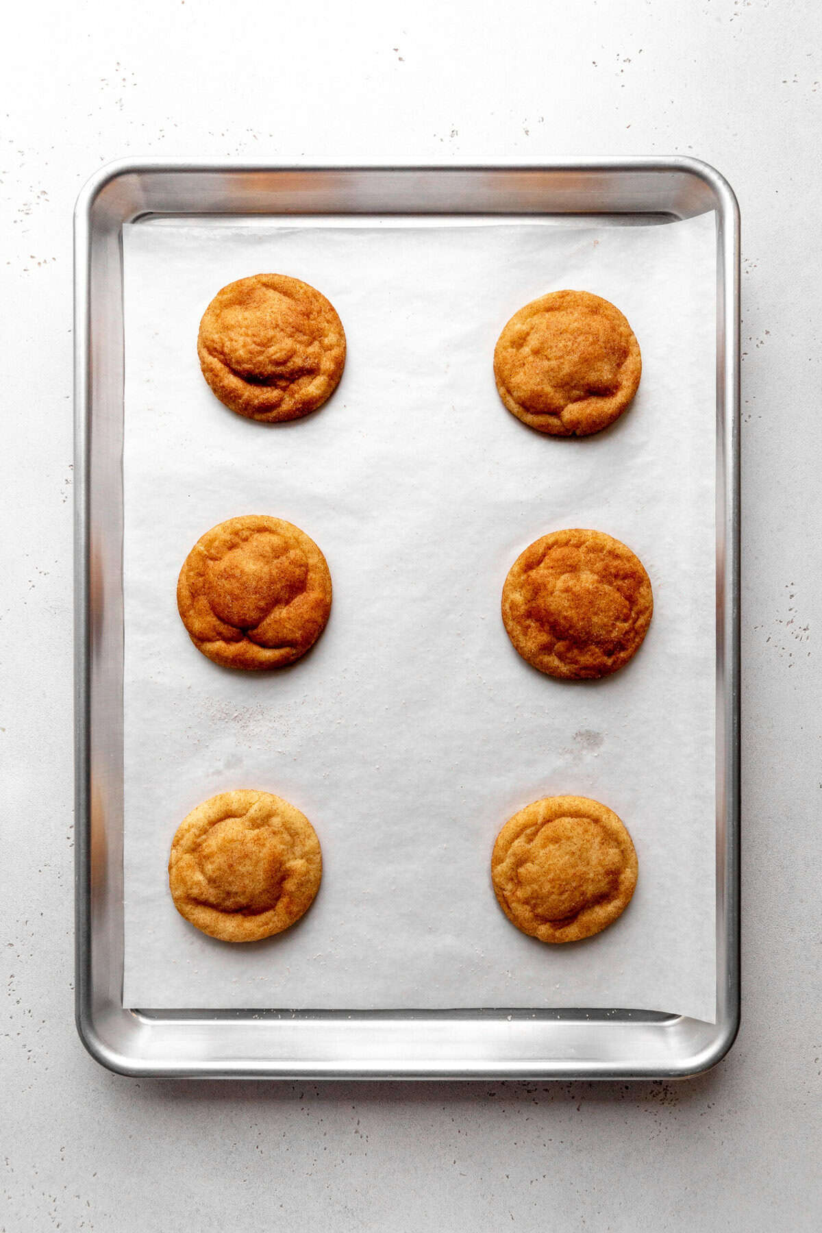 Baked snickerdoodle cookies on a baking sheet.