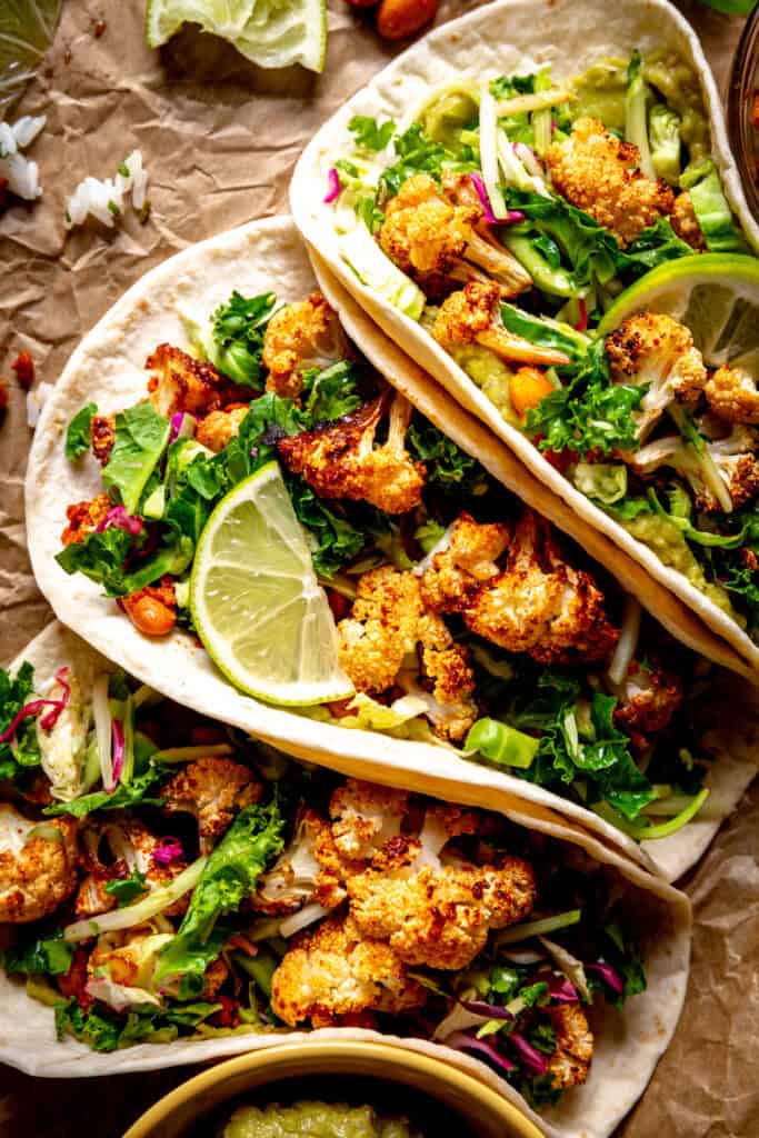 Cauliflower taco topped with cilantro slaw and a lime wedge.