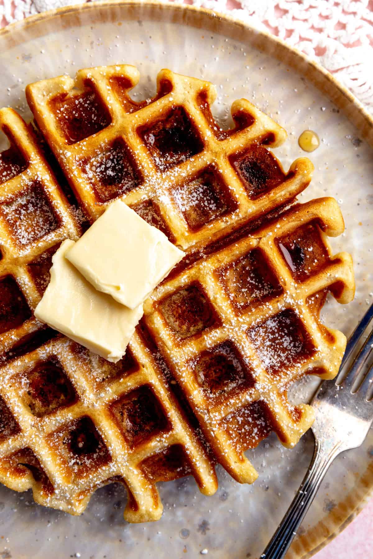 Vegan Belgian waffle squares drenched in maple syrup.