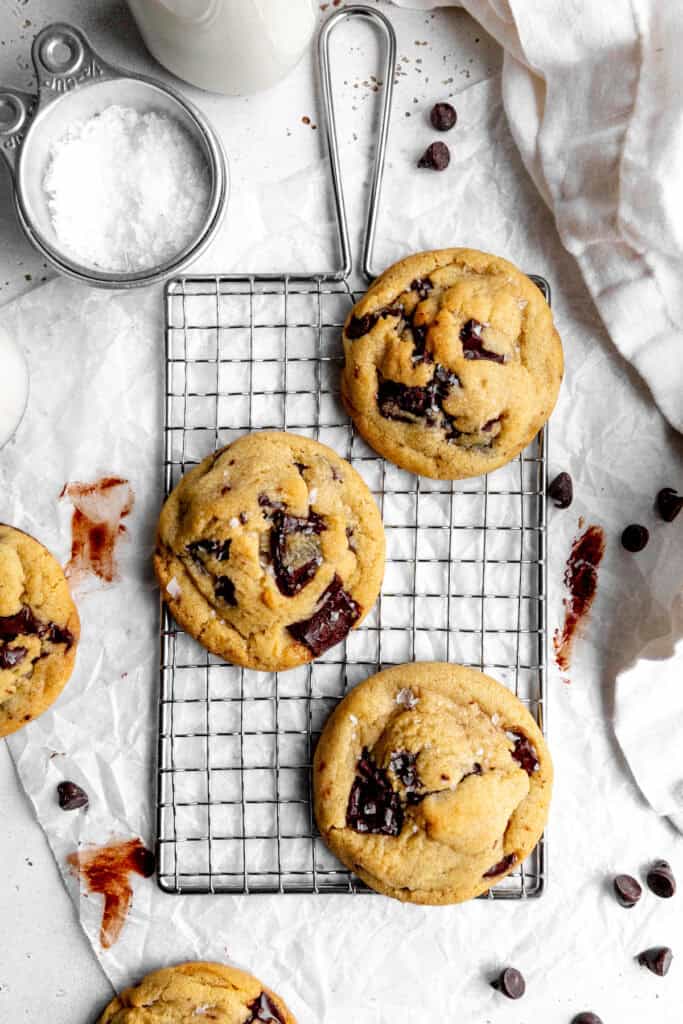 Vegan chocolate chip cookies on a wire rack and a glass of milk.