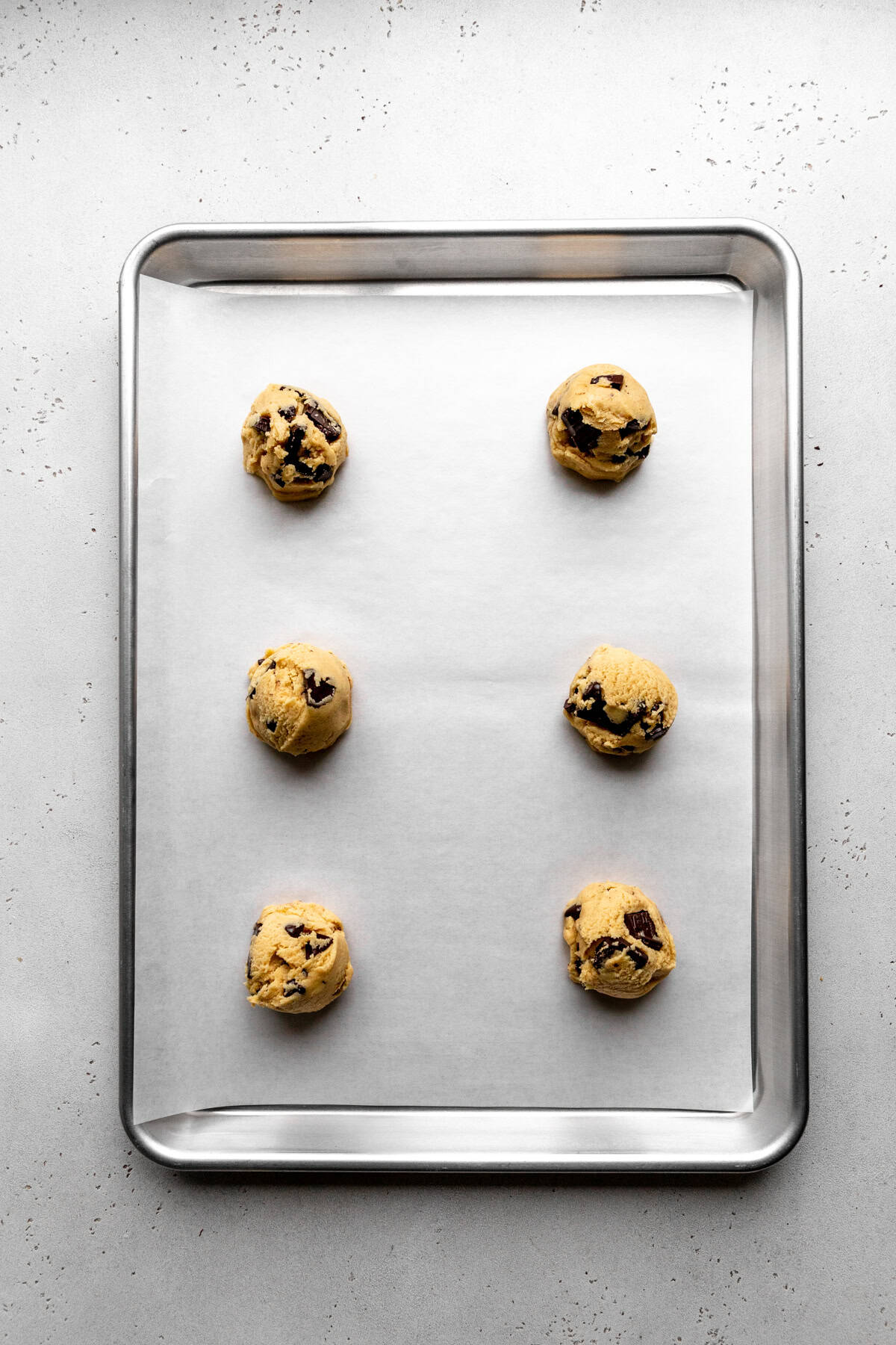 Unbaked chocolate chip cookies on a baking sheet.