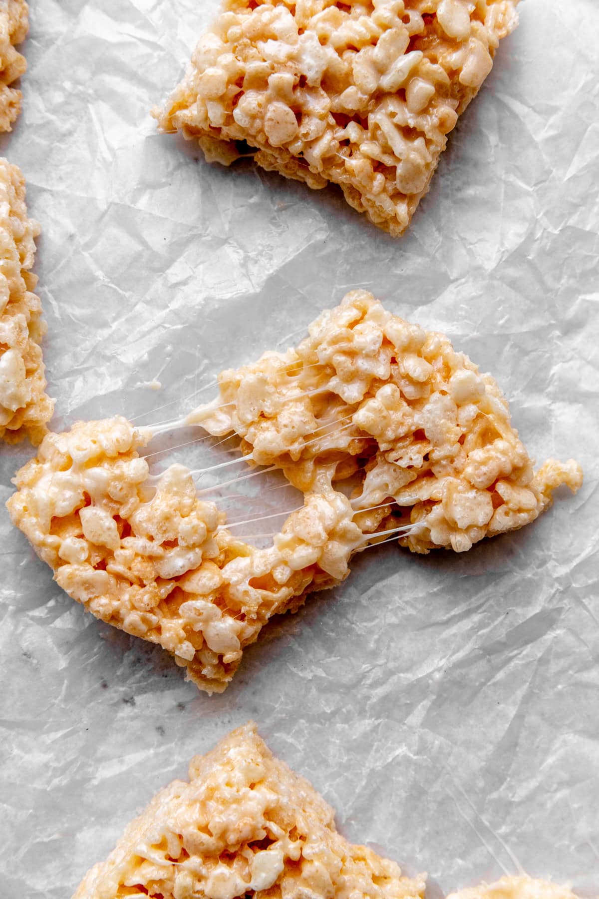 Rice krispie treat being pulled apart with gooey marshmallow strands.