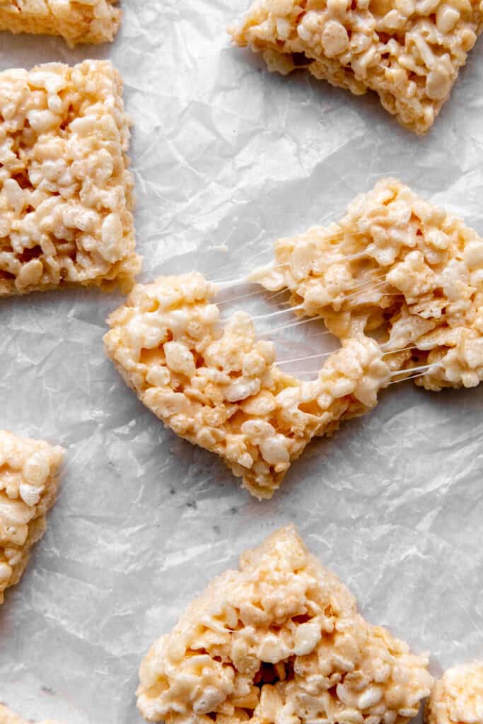 Rice krispie treat being pulled apart with gooey marshmallow strands.