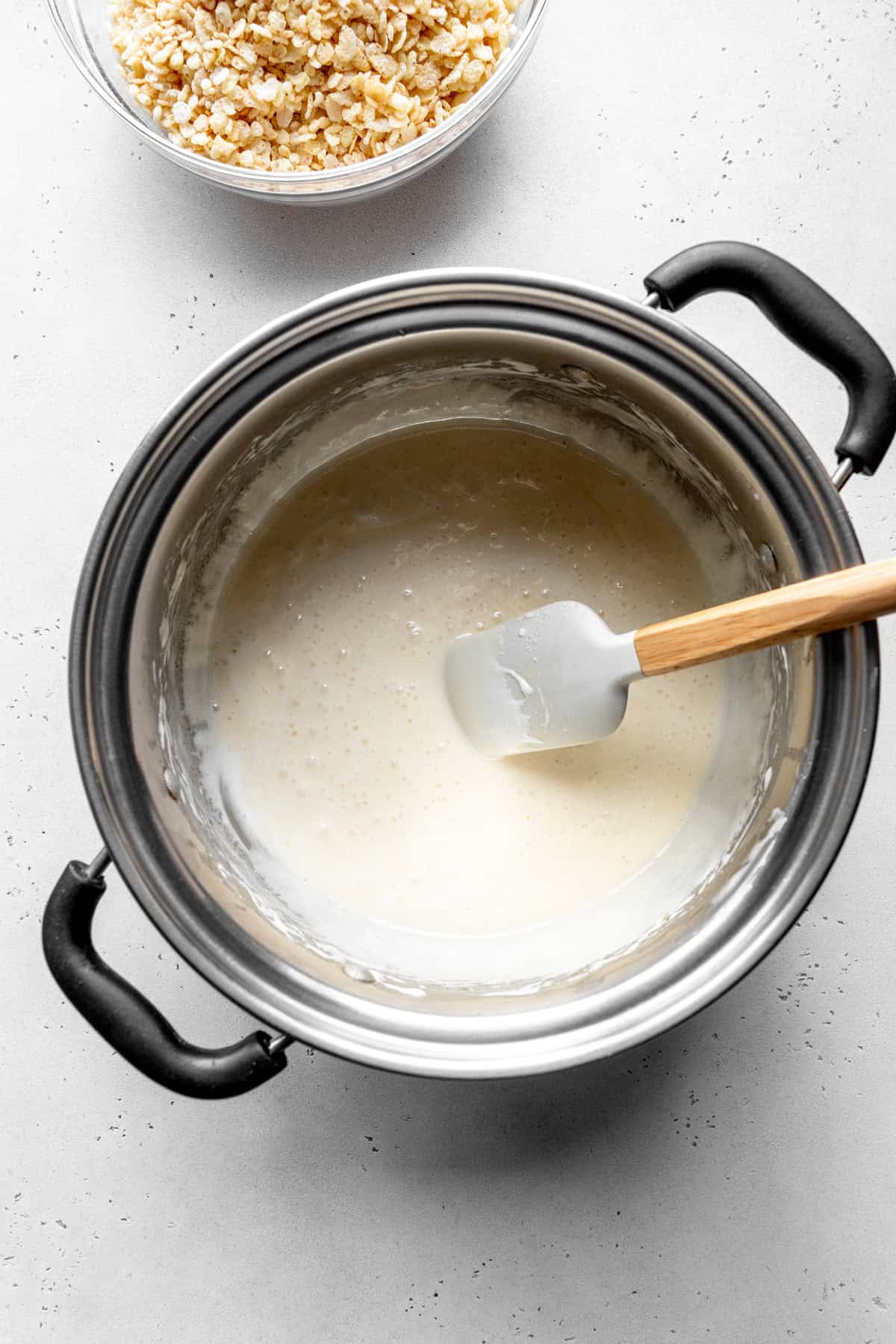 Pot of melted butter and marshmallows with a rubber spatula.