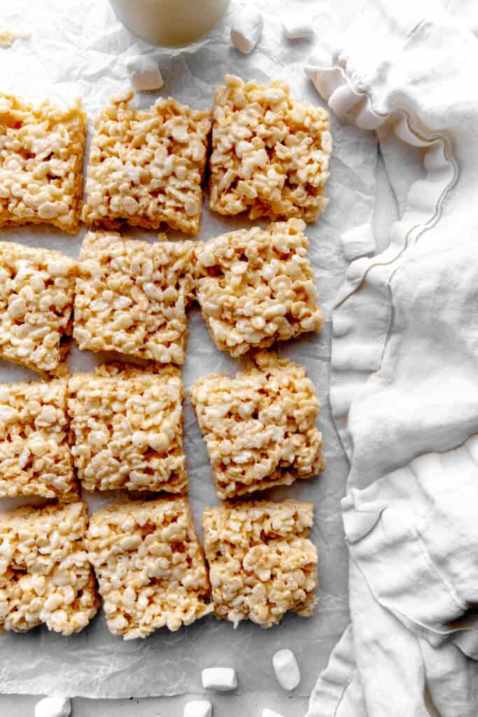 Rice krispie treats, a glass of milk and a white linen napkin.