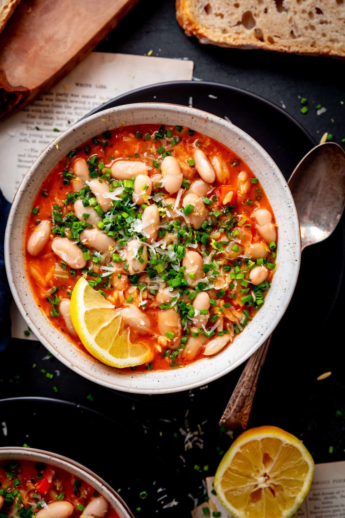 Bowl of tomato orzo soup, half a lemon and a spoon.