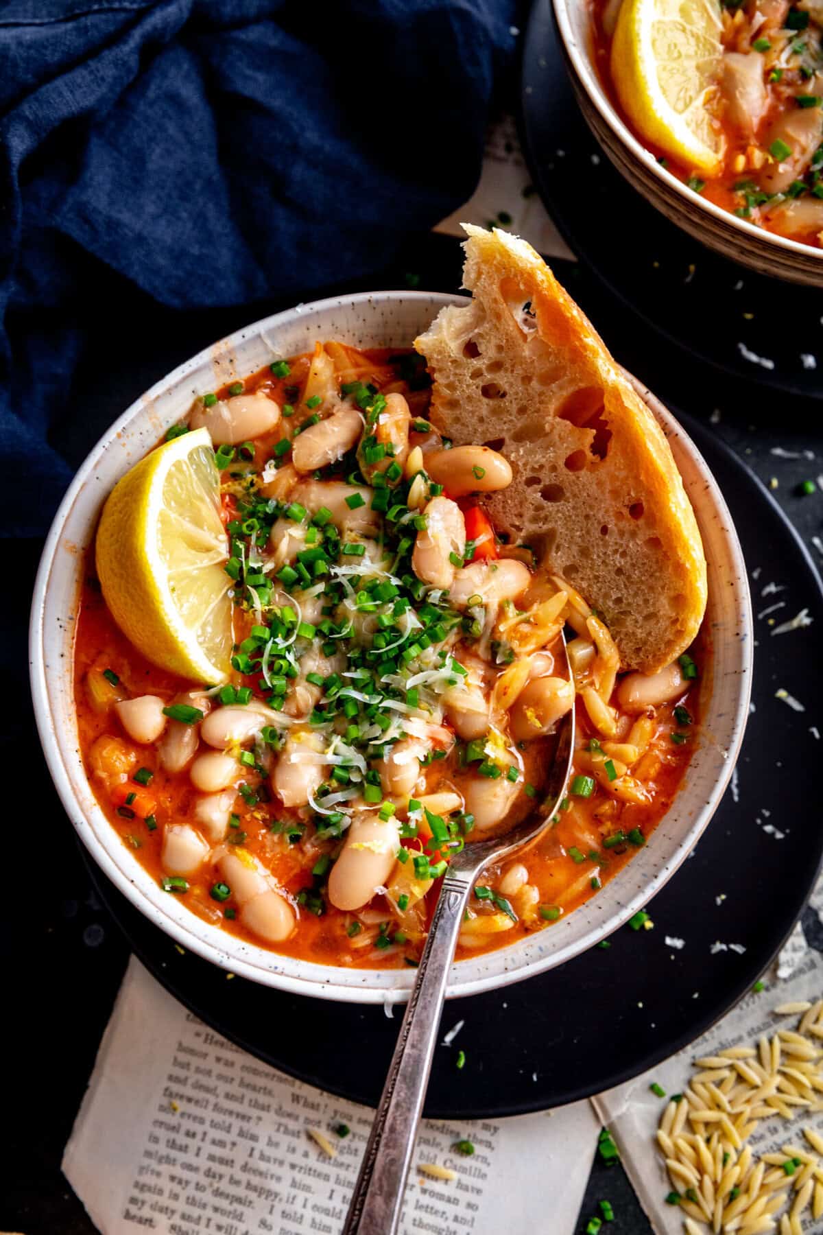 Bread dipped into a bowl of vegetable orzo tomato soup.