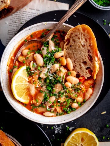 Bread dipped into a bowl of vegetable orzo tomato soup.
