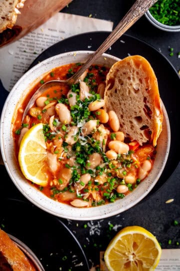 Bread dipped into a bowl of vegetable orzo tomato soup.