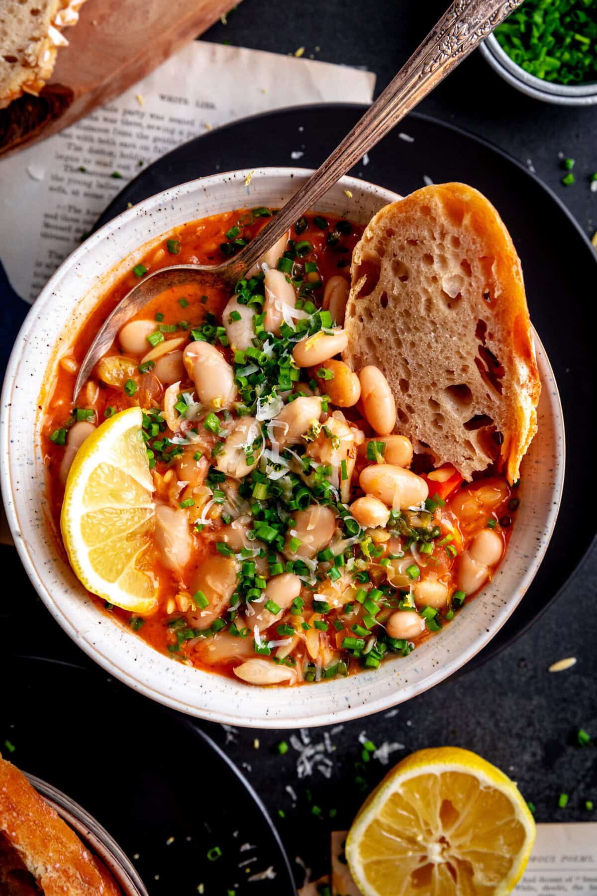 Bread dipped into a bowl of vegetable orzo tomato soup.
