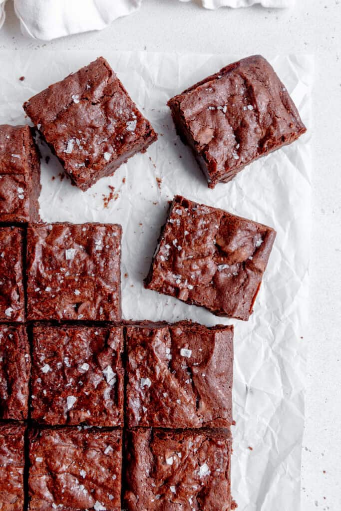 Brownies cut into squares and topped with flaky sea salt and a linen napkin.