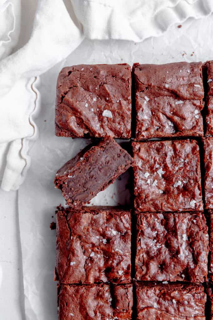 Vegan brownies on a white surface with a white linen napkin.